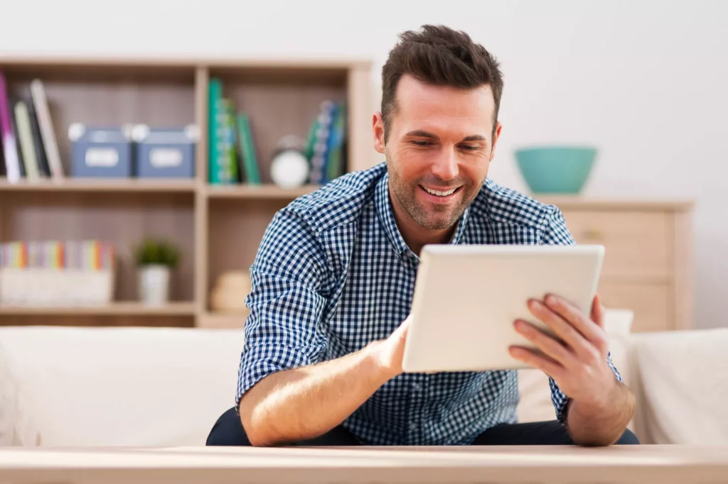Homme souriant devant une tablette numérique
